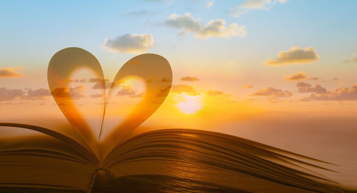 Imagem de um coração feito com páginas de um livro com uma paisagem enrolarada ao fundo, simbolizando o significado do amor na Bíblia.